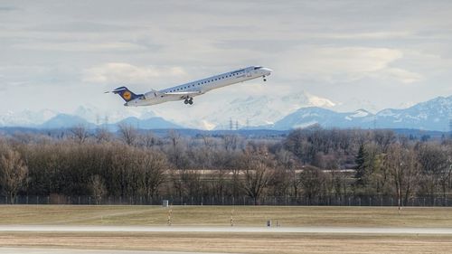 Airplane flying over land against sky