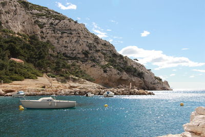 Sailboats on sea by mountains against sky