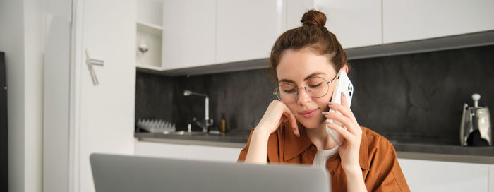 Side view of young man using phone while sitting at home