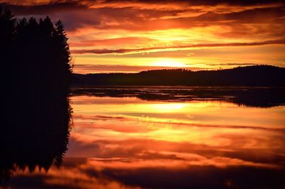 Scenic view of dramatic sky over lake during sunset