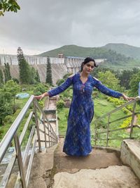 Full length of woman standing on railing against mountain