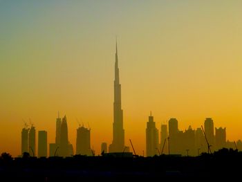 Silhouette burj khalifa against orange sky