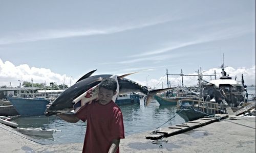 Fisherman carrying dead tuna at harbor
