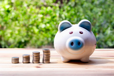 Stacks of coins and piggy bank on table