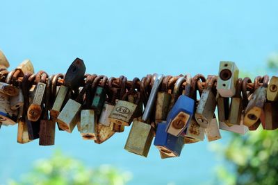 Close-up of padlocks hanging on rope against sky