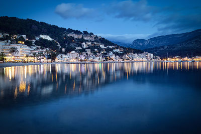 Scenic view of lake by illuminated buildings against sky