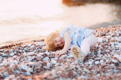 Cute boy lying on pebbles at beach