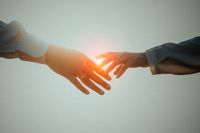 Cropped hands of couple against sky