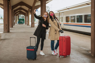 Woman with umbrella walking on railroad track