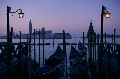 View of boats moored in canal at sunset