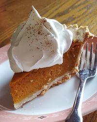 Close-up of pumpkin pie with whipped cream on plate