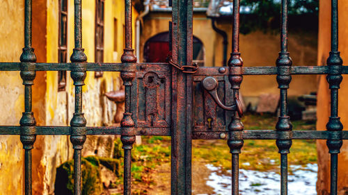 Close-up of rusty metal fence against old building