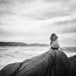 Landscape of girl and rock against sea