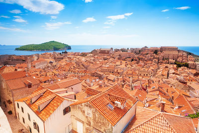 Aerial view of townscape by sea against sky