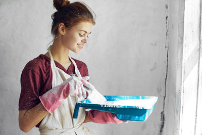 Side view of young woman standing against wall