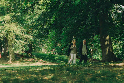 Woman standing by tree trunks in forest