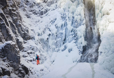 High angle view of man on snow covered mountains by waterfall during winter