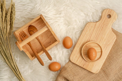 High angle view of egg and wheat with wooden eating utensils on table