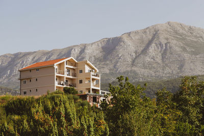 Houses by trees and mountains against clear sky