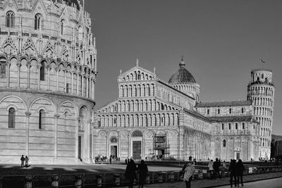 People in front of historic building against sky in city