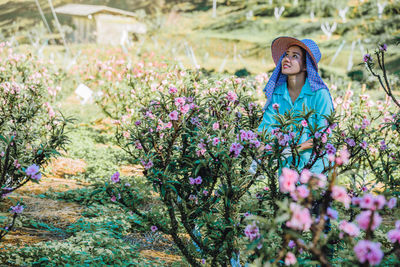 Female researcher standing amidst pink flowers on land