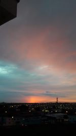 Illuminated buildings against sky at sunset