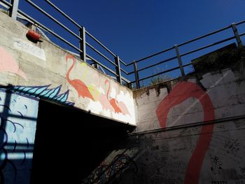 Low angle view of graffiti on wall against clear sky