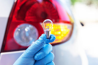 Mechanic holding light bulb against car