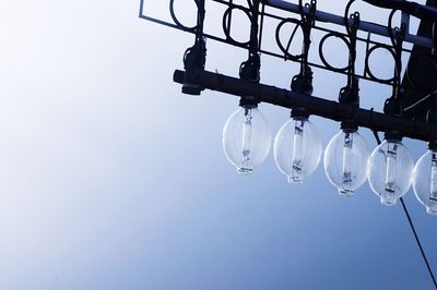 Low angle view of illuminated lighting equipment against clear sky