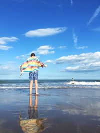 Rear view of man standing on beach against sky