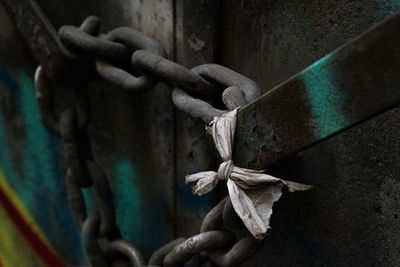 Close-up of rusty chain on a rusty door and a plastic knot 