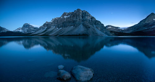 Scenic view of lake and snowcapped mountains against blue sky