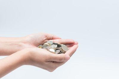 Close-up of hand holding ring over white background