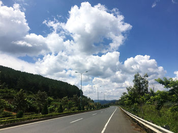 Road by trees against sky
