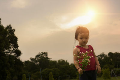 Rear view of boy standing against sky during sunset