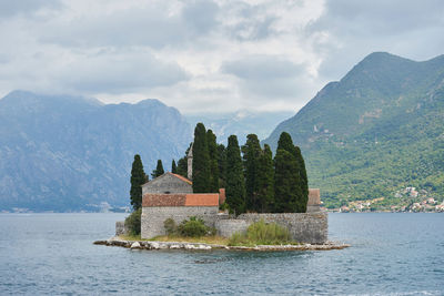 Built structure by trees and mountains against sky