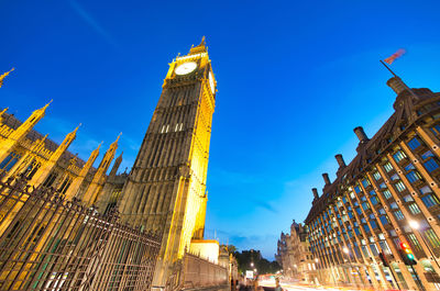 Low angle view of illuminated buildings against blue sky