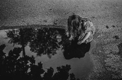 Low angle view of girl with reflection in puddle