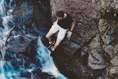 High angle view of man sitting on rock by river