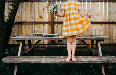 Young girl standing on pinic table with yellow dress and flowers