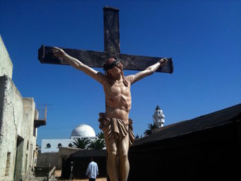Crucifix against clear blue sky on sunny day