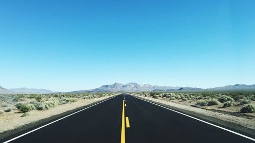 Empty road against mountains and sky