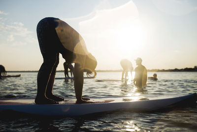 People exercising on paddleboard during sunset