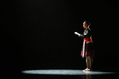 Side view of man standing against black background