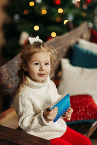 Portrait of cute girl sitting on sofa at home