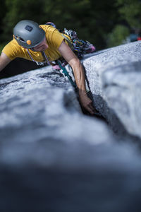 Man placing protection while lead rock climbing wide crack on granite