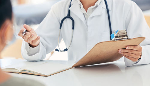 Midsection of doctor examining patient in hospital