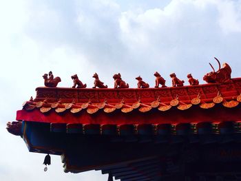 Low angle view of statues on temple roof against sky