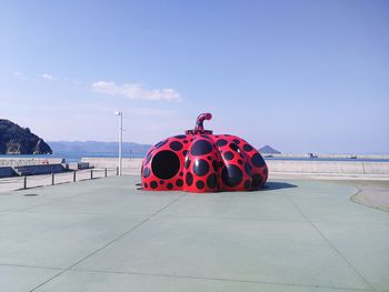 Red umbrella on sea shore against sky