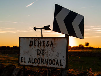 Information sign on field against sky during sunset